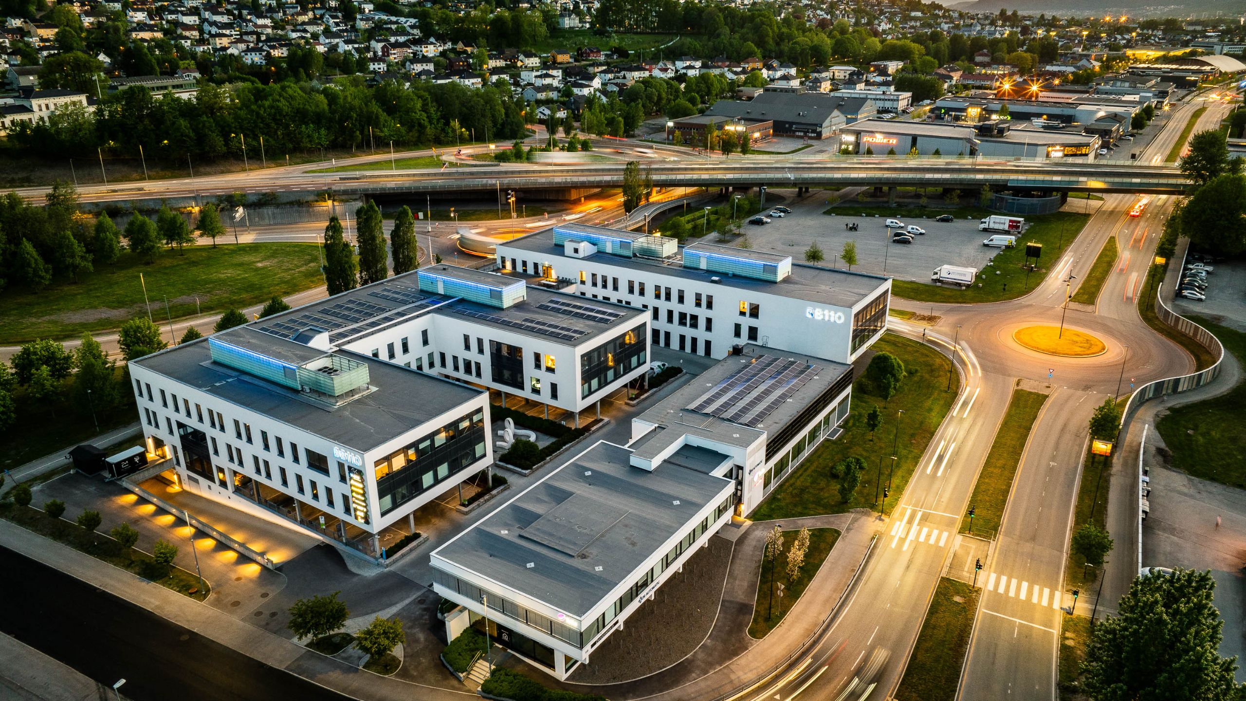 BB110, the Stax Infra datacenter in Drammen, Norway, at blue hour with solar panels visible on the roof and warm uplighting along the facade